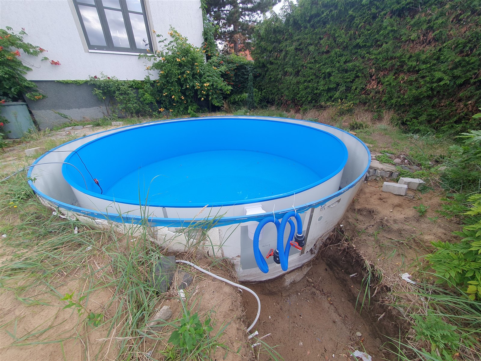 Neuer runder Stahlwandpool mit blauer Innenauskleidung vor dem Holzdeckbau