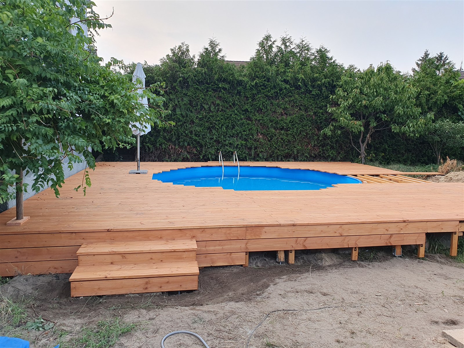 Geschlossenes Holzdeck mit breiter Zugangstreppe am neuen Stahlwandpool