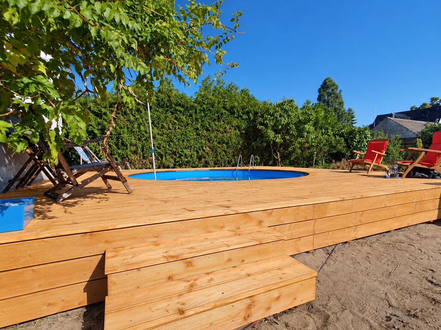 Holzdeck mit Stufe und eingelassenem Pool im Garten