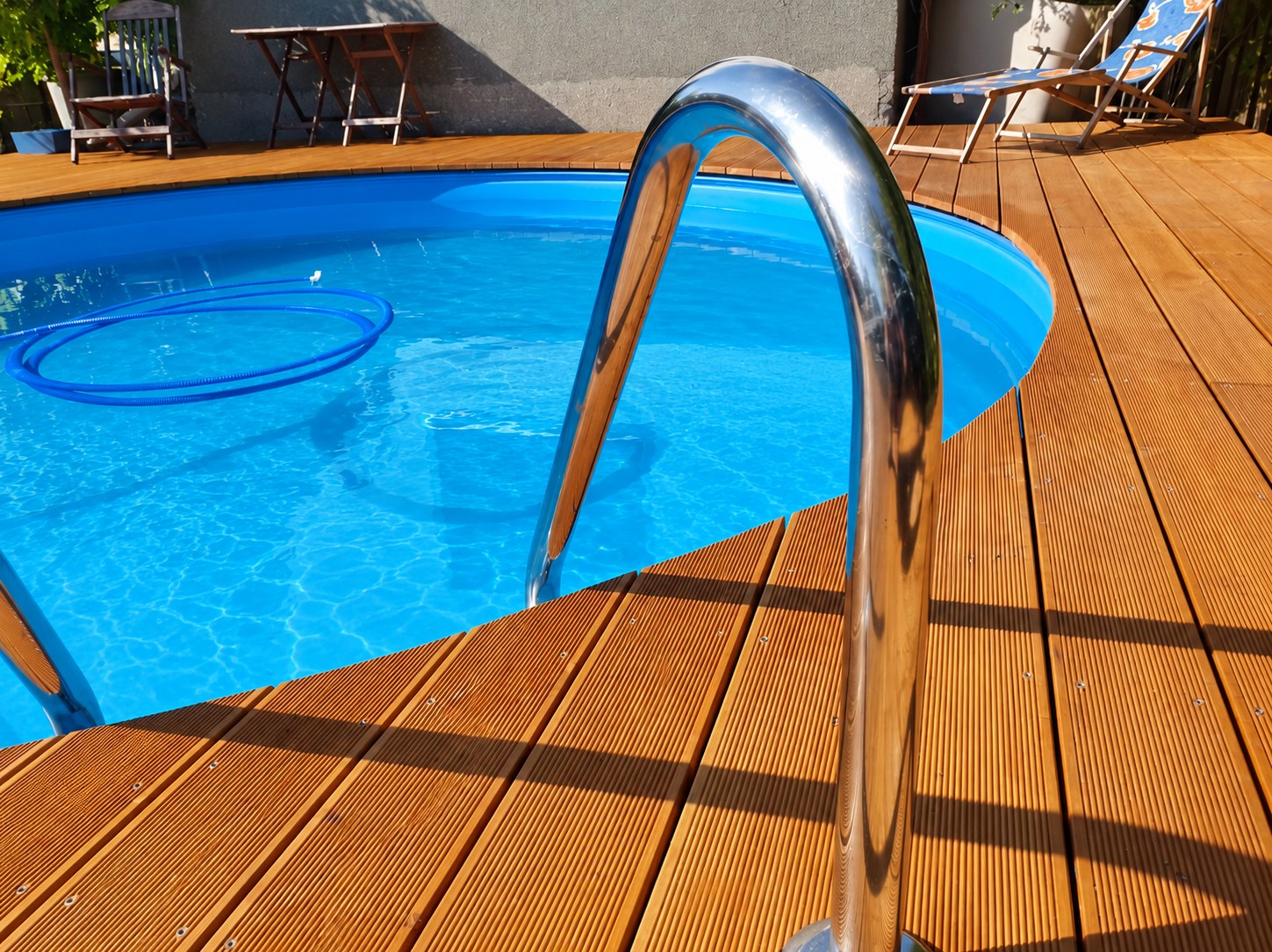Poolrand mit Holzdeck und Edelstahlleiter im Detail