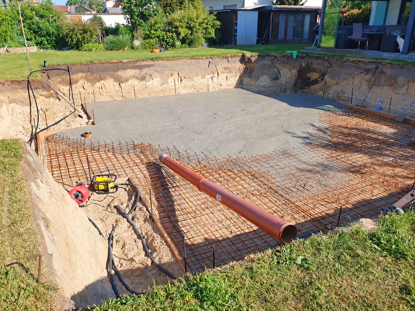 Bewehrung und Vorbereitung einer Betonplatte in einer ausgehobenen Baugrube
