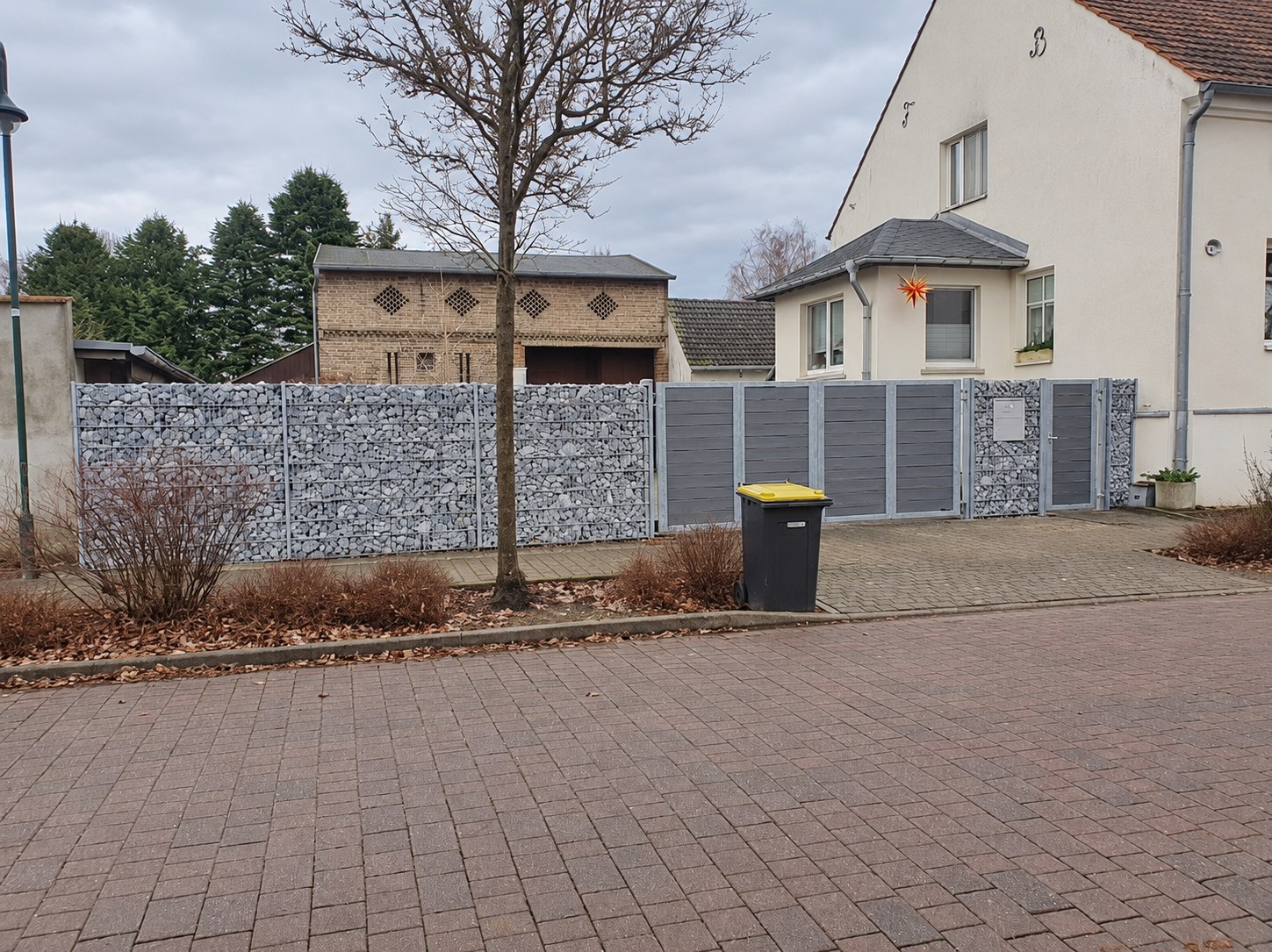 Grundstückseinfassung aus Gabionen und grauem Sichtschutztor